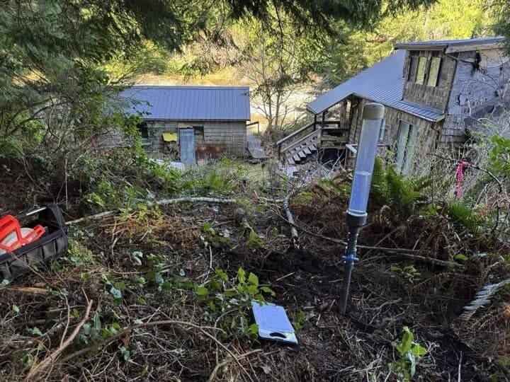 Permeameter set up for a percolation test on a steep, forested lot beside two cabins in Bamfield, BC